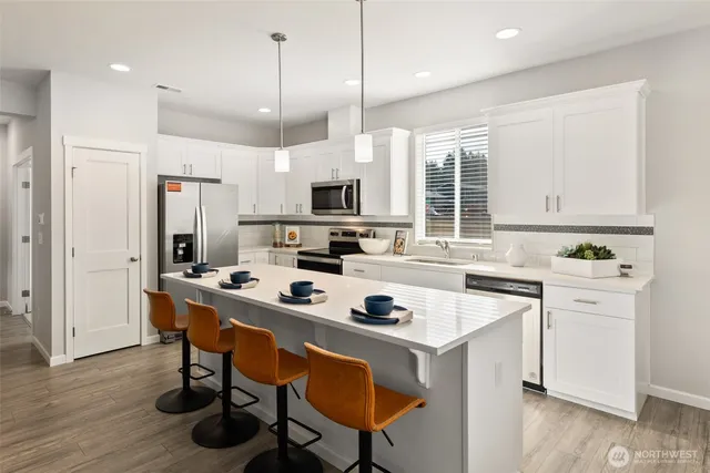 a kitchen with a stove a refrigerator and a dining table with wooden floor