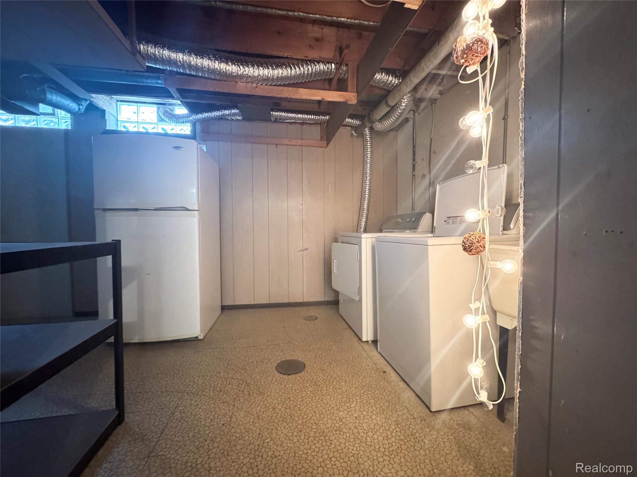4386 15 Mile Road, Unit 64 Sterling Heights, MI 48310 - Photo 21 of 23 Laundry area featuring a washer and dryer, exposed ceiling joists, and glass block windows