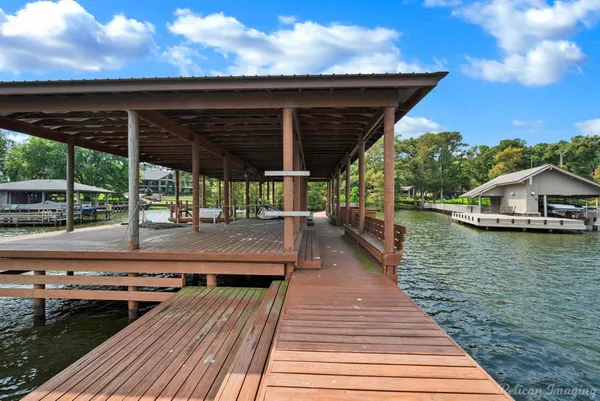 a view of a roof deck with table and chairs a barbeque with wooden floor and fence