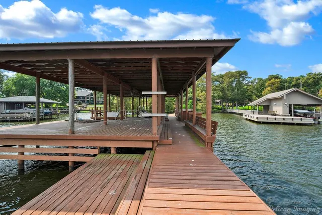 a view of a roof deck with table and chairs a barbeque with wooden floor and fence