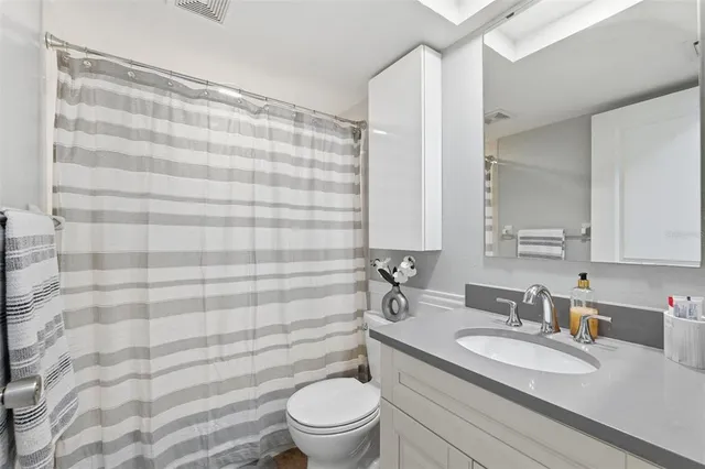 a bathroom with a granite countertop sink a toilet and a mirror