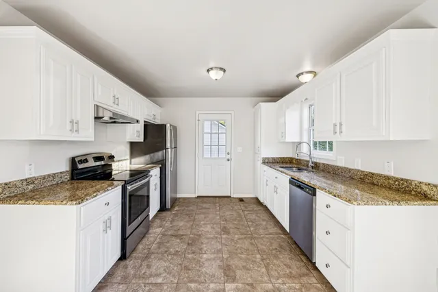 a large kitchen with stainless steel appliances granite countertop a stove a sink dishwasher and a refrigerator