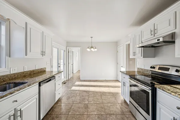 a kitchen with granite countertop a stove sink and cabinets
