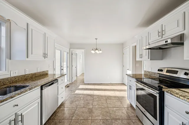 a kitchen with granite countertop a stove sink and cabinets