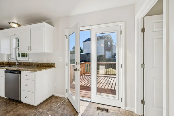 a kitchen with granite countertop a refrigerator and white cabinets