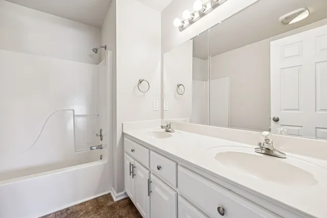 a bathroom with a sink double vanity granite tub shower and a mirror