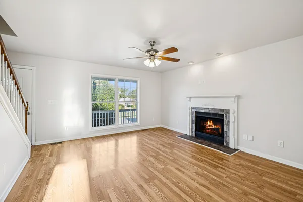 an empty room with windows fireplace and a ceiling fan