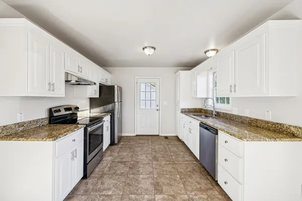 a large kitchen with stainless steel appliances granite countertop a stove a sink dishwasher and a refrigerator