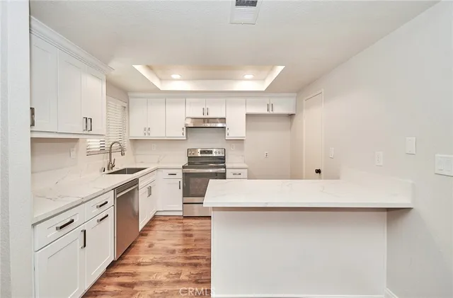 a kitchen with stainless steel appliances a refrigerator sink and white cabinets