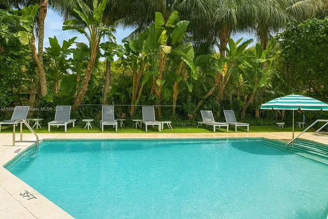a view of a swimming pool with lawn chairs under an umbrella