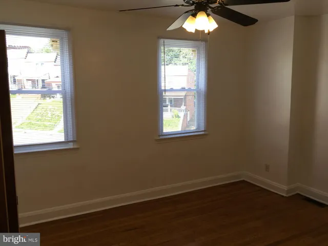 an empty room with wooden floor closet and fan