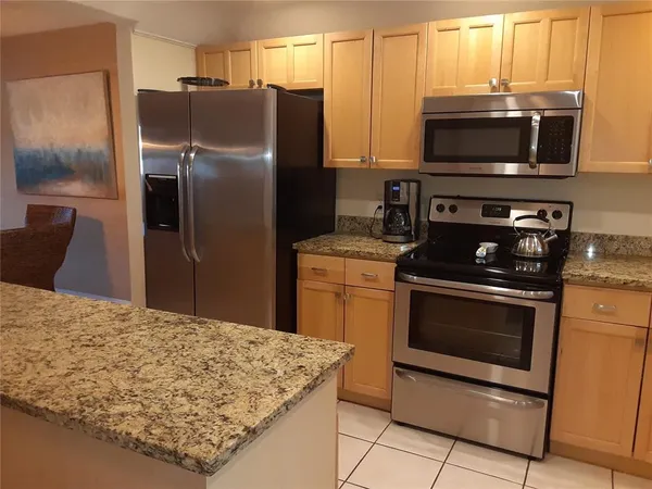 a kitchen with stainless steel appliances kitchen island granite countertop a stove refrigerator and microwave