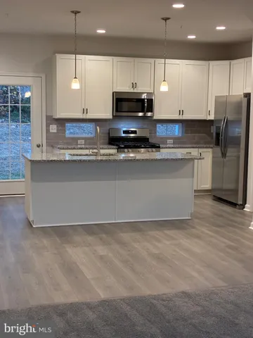 a large kitchen with stainless steel appliances granite countertop a stove a sink and a microwave