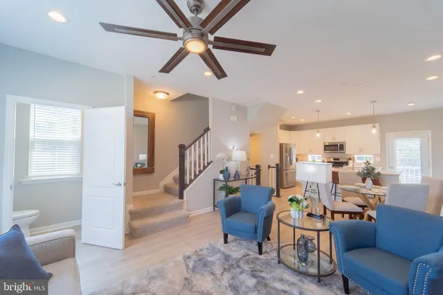 a living room with furniture kitchen view and a wooden floor