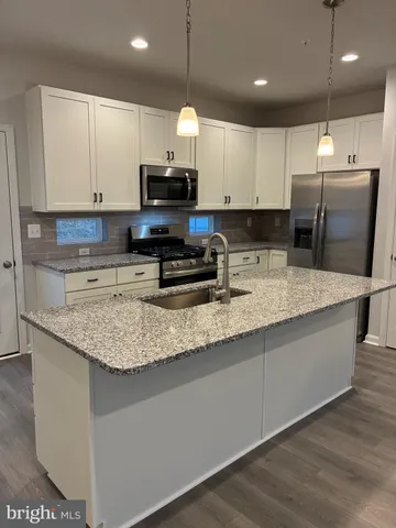 a kitchen with kitchen island granite countertop a sink a counter top space appliances and cabinets