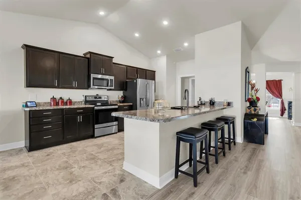 a kitchen with stainless steel appliances kitchen island granite countertop a refrigerator and a stove top oven