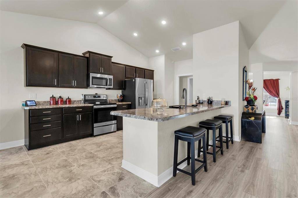 3455 Whispy Court Spring Hill, FL 34609 - Photo 5 of 42 a kitchen with stainless steel appliances kitchen island granite countertop a refrigerator and a stove top oven