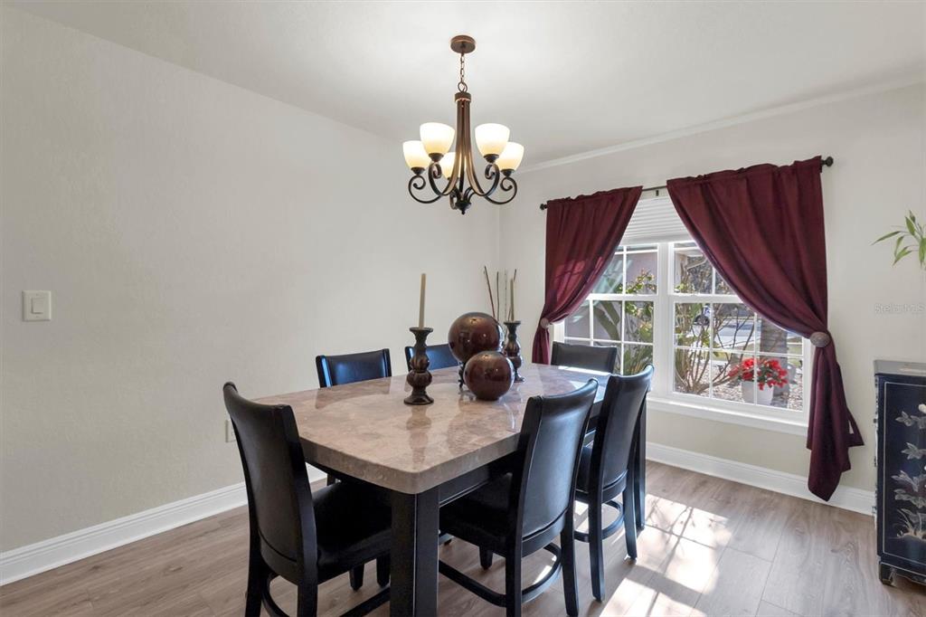 3455 Whispy Court Spring Hill, FL 34609 - Photo 6 of 42 a dining room with wooden floor a chandelier a wooden table and chairs