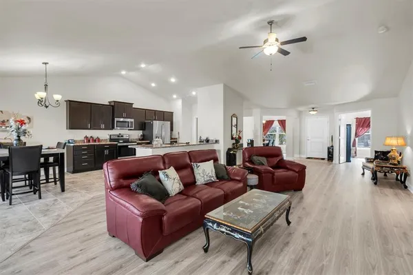 a living room with furniture kitchen view and a wooden floor