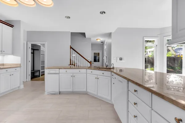 a large white kitchen with a sink and dishwasher with a large window