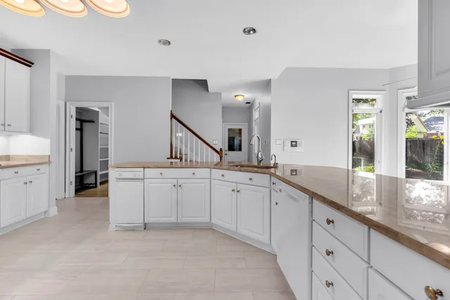 a large white kitchen with a sink and dishwasher with a large window