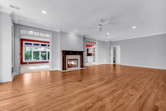 an empty room with wooden floor fireplace and windows
