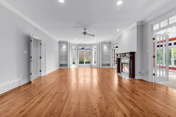 a view of an empty room with wooden floor and a window