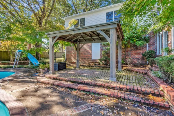 a view of a wooden house with a small yard and large tree