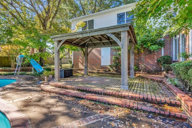 a view of a wooden house with a small yard and large tree
