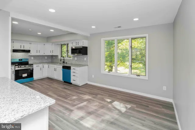 a kitchen with stainless steel appliances granite countertop a stove a sink and a microwave