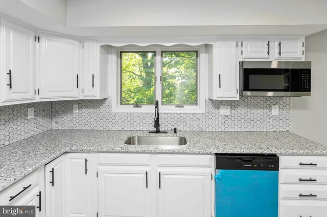 a kitchen with stainless steel appliances granite countertop a stove top oven a sink dishwasher and a refrigerator with wooden floor