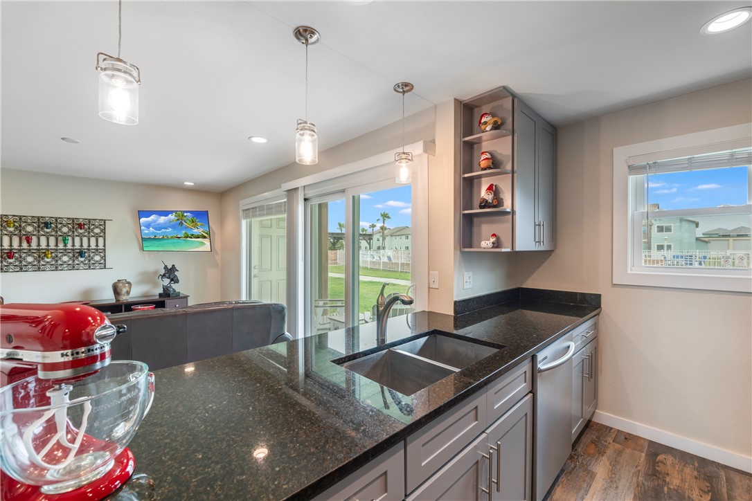 230 Cut-Off Road, Unit 101 Port Aransas, TX 78373 - Photo 12 of 30 a kitchen with kitchen island granite countertop a sink a counter top space and living room area