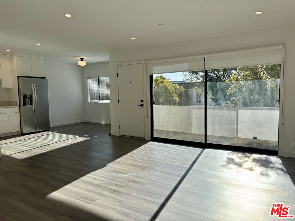 1264 9th Street, Unit J Santa Monica, CA 90401 - Photo 3 of 23 a view of an empty room with wooden floor and a window