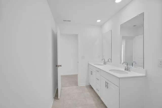 a bathroom with a double vanity sink toilet mirror and bathtub