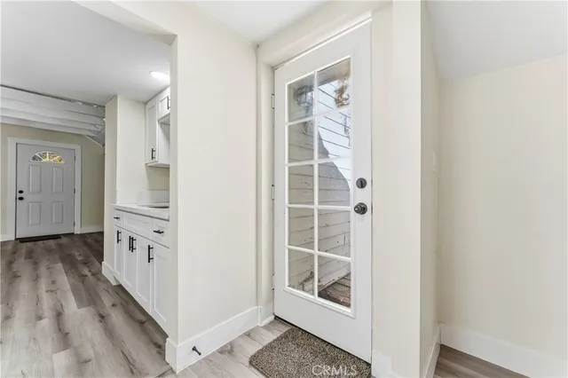 wooden floor with white cabinets and window