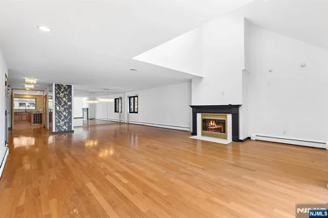a view of empty room with wooden floor and a fireplace