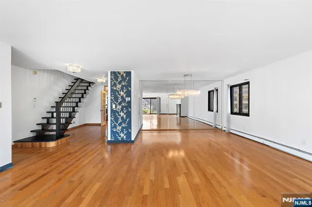 a view of an empty room with wooden floor and stairs
