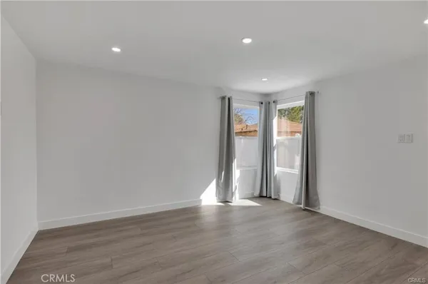 a view of an empty room with wooden floor and window