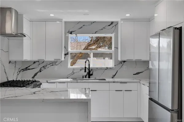 a kitchen with stainless steel appliances granite countertop a sink and a refrigerator