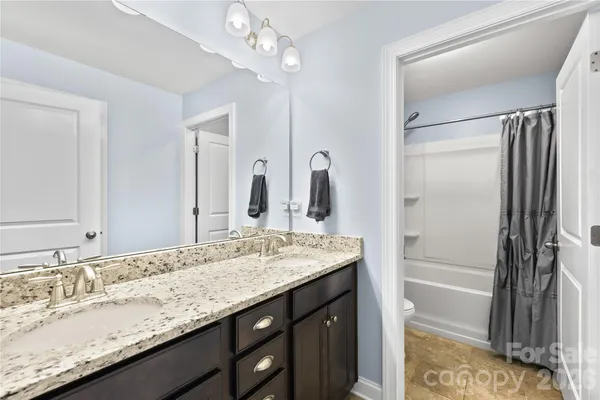 a bathroom with a granite countertop sink a mirror and a bathtub
