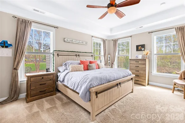 a spacious bedroom with a bed a window and a dresser