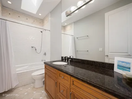 a bathroom with a granite countertop sink a toilet a large mirror and shower