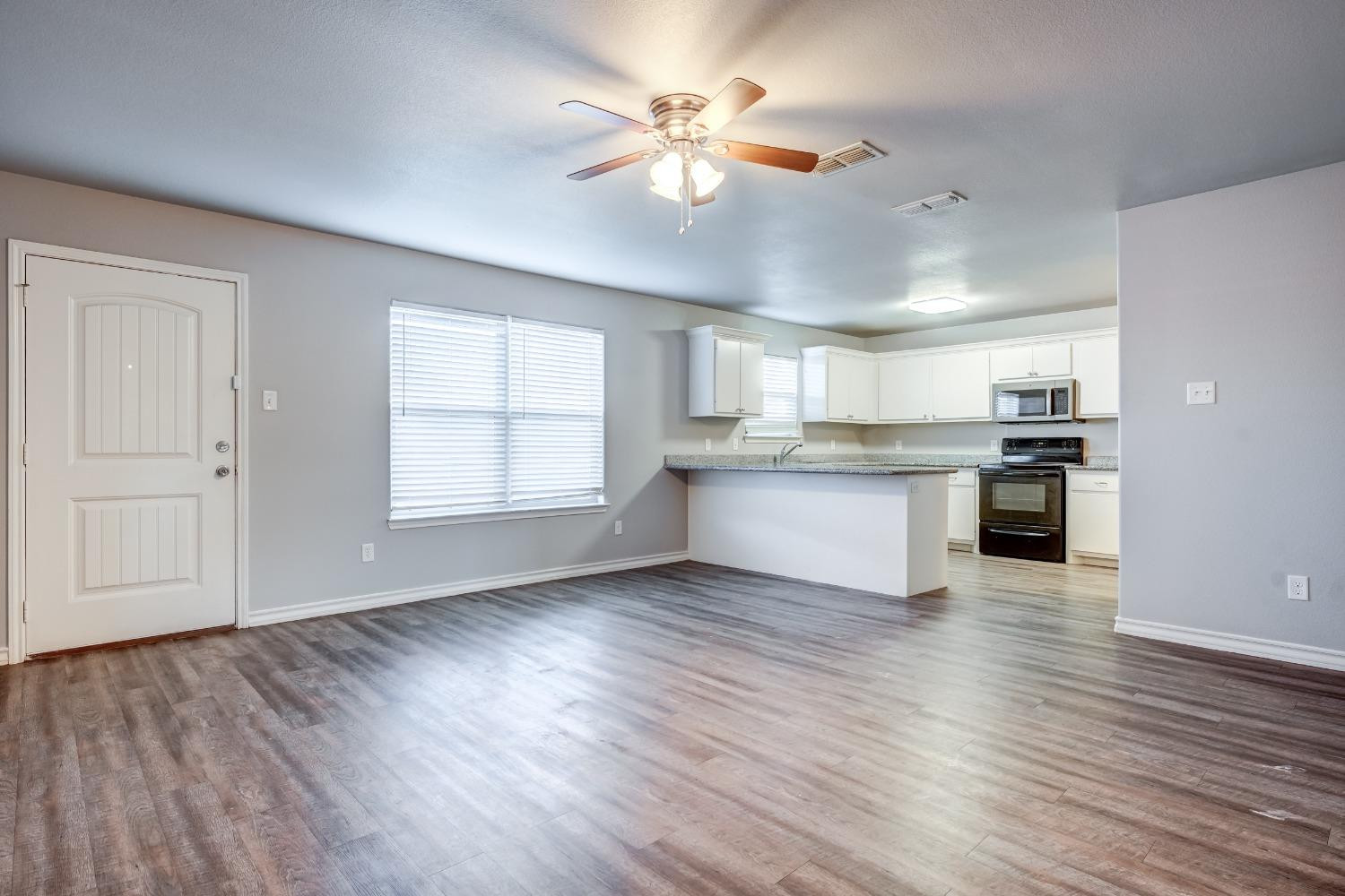 3450 Itasca Street Lubbock, TX 79415 - Photo 4 of 24 an empty room with wooden floor kitchen view and a window