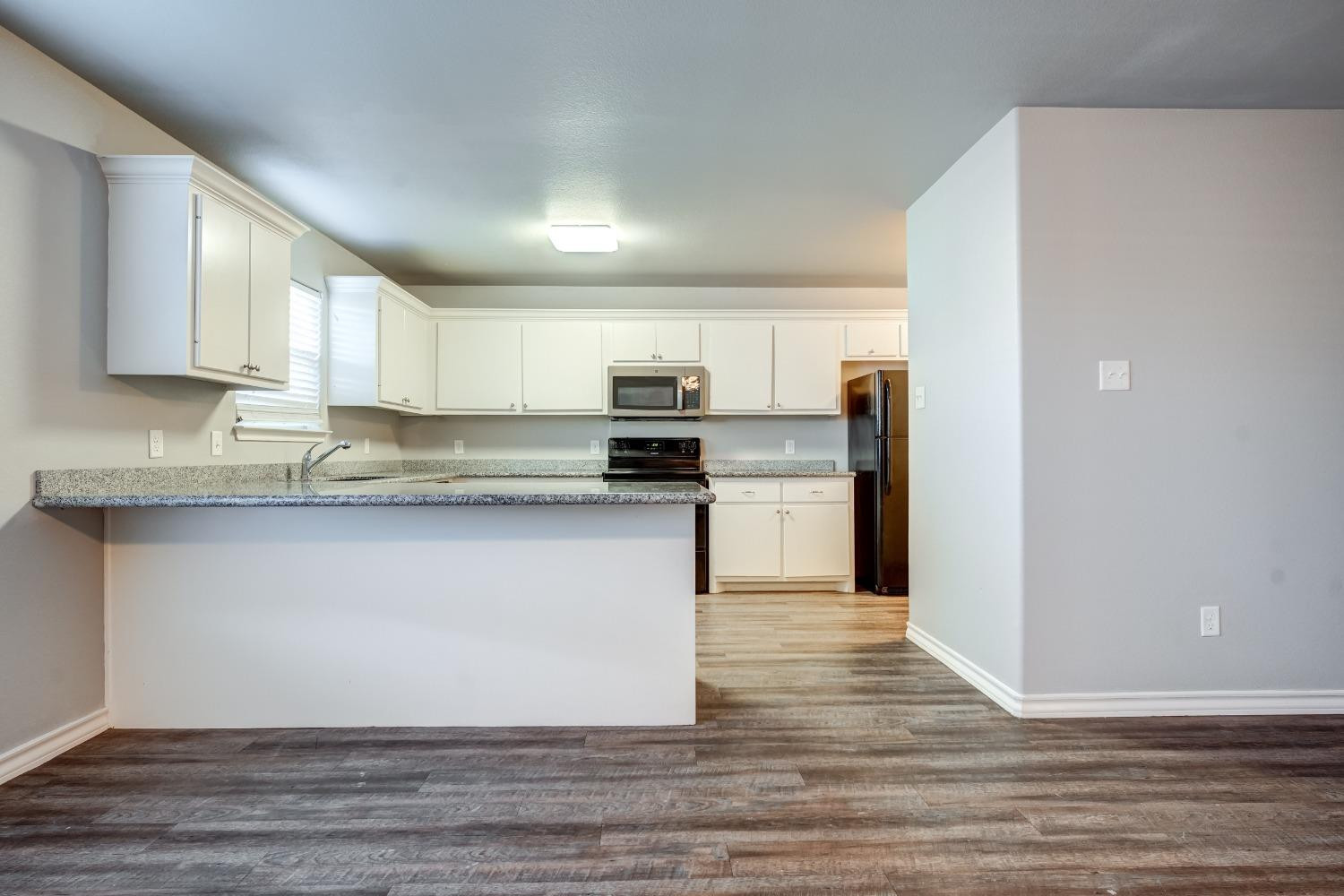 3450 Itasca Street Lubbock, TX 79415 - Photo 7 of 24 a kitchen with granite countertop a refrigerator and a stove top oven