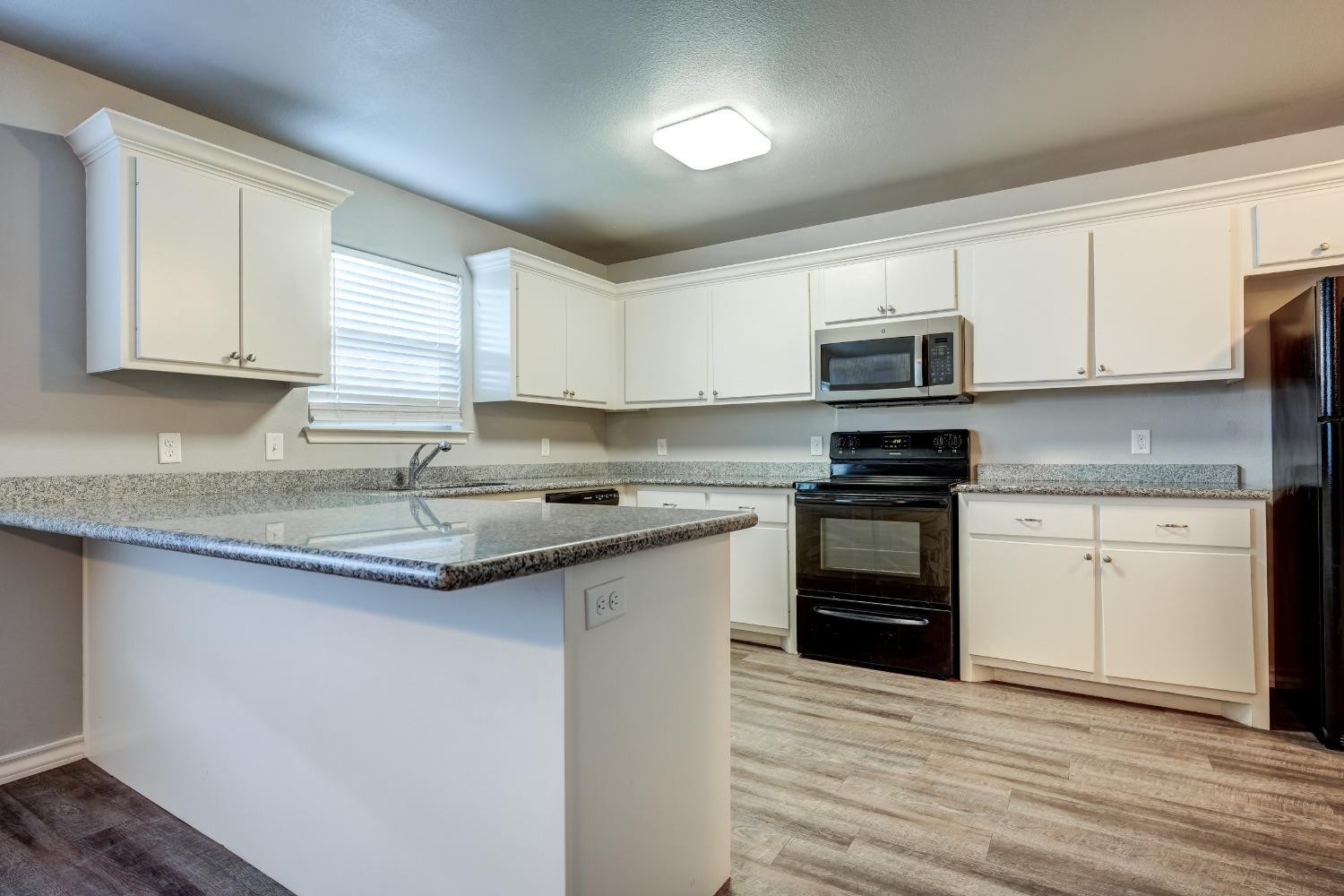3450 Itasca Street Lubbock, TX 79415 - Photo 9 of 24 a kitchen with kitchen island granite countertop a sink stainless steel appliances and white cabinets
