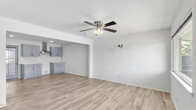 a view of kitchen and empty room with wooden floor and window