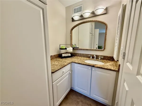 a bathroom with a granite countertop sink and a mirror