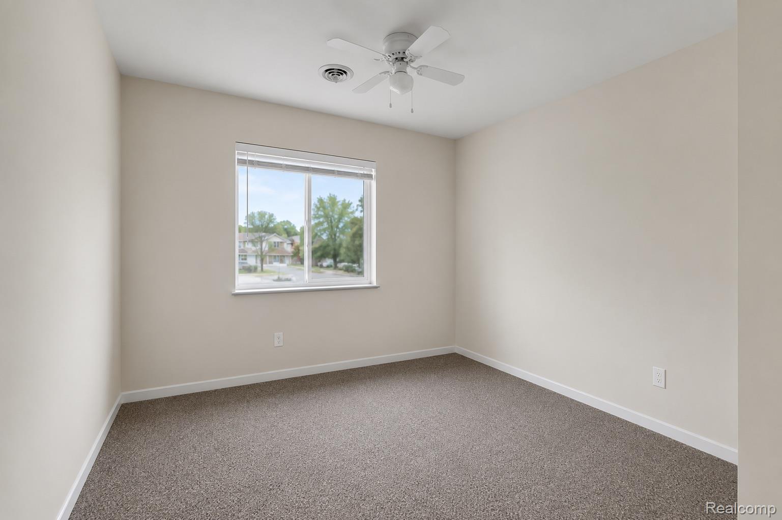 5223 Allen Road Allen Park, MI 48101 - Photo 10 of 12 Neutral-toned room featuring a large window with blinds, light-colored walls, and textured carpet flooring