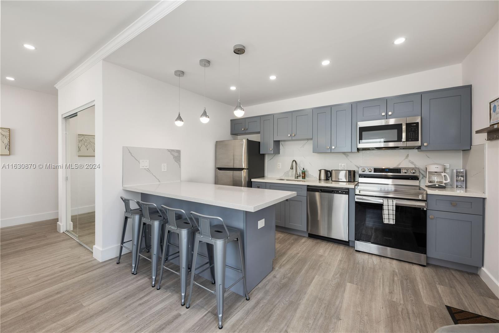 1648 Southwest 7th Street Miami, FL 33135 - Photo 14 of 23 a kitchen with stainless steel appliances granite countertop a stove top oven a sink dishwasher a refrigerator and a dining table with wooden floor