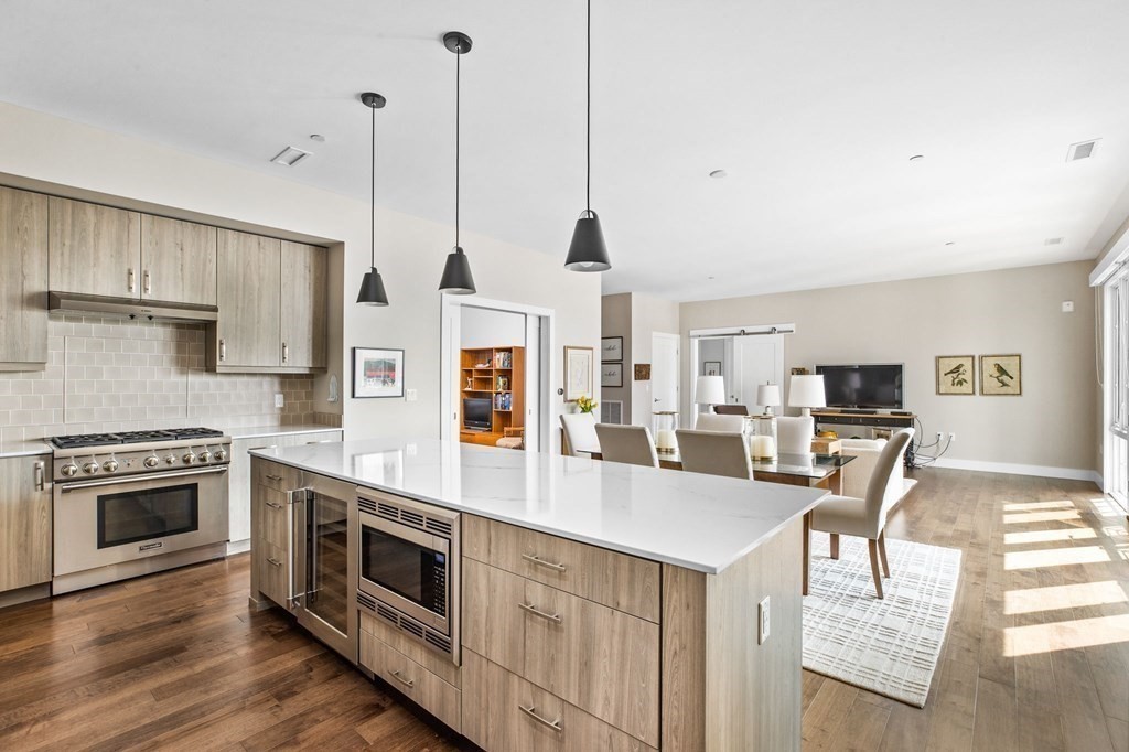 10 Shipyard Drive, Unit 408 Hingham, MA 02043 - Photo 6 of 26 a kitchen with stainless steel appliances granite countertop a stove top oven a sink dishwasher and a refrigerator with wooden floor